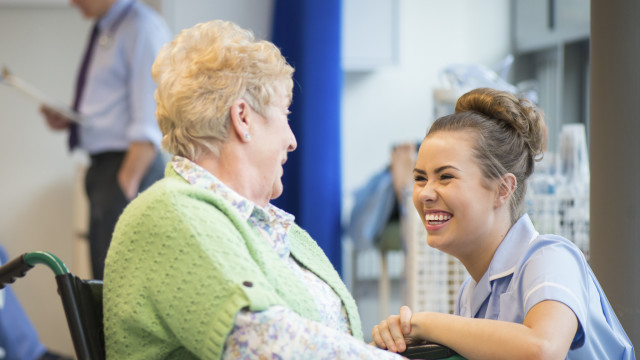 senior woman laughing with nurse on the ward or nursing home